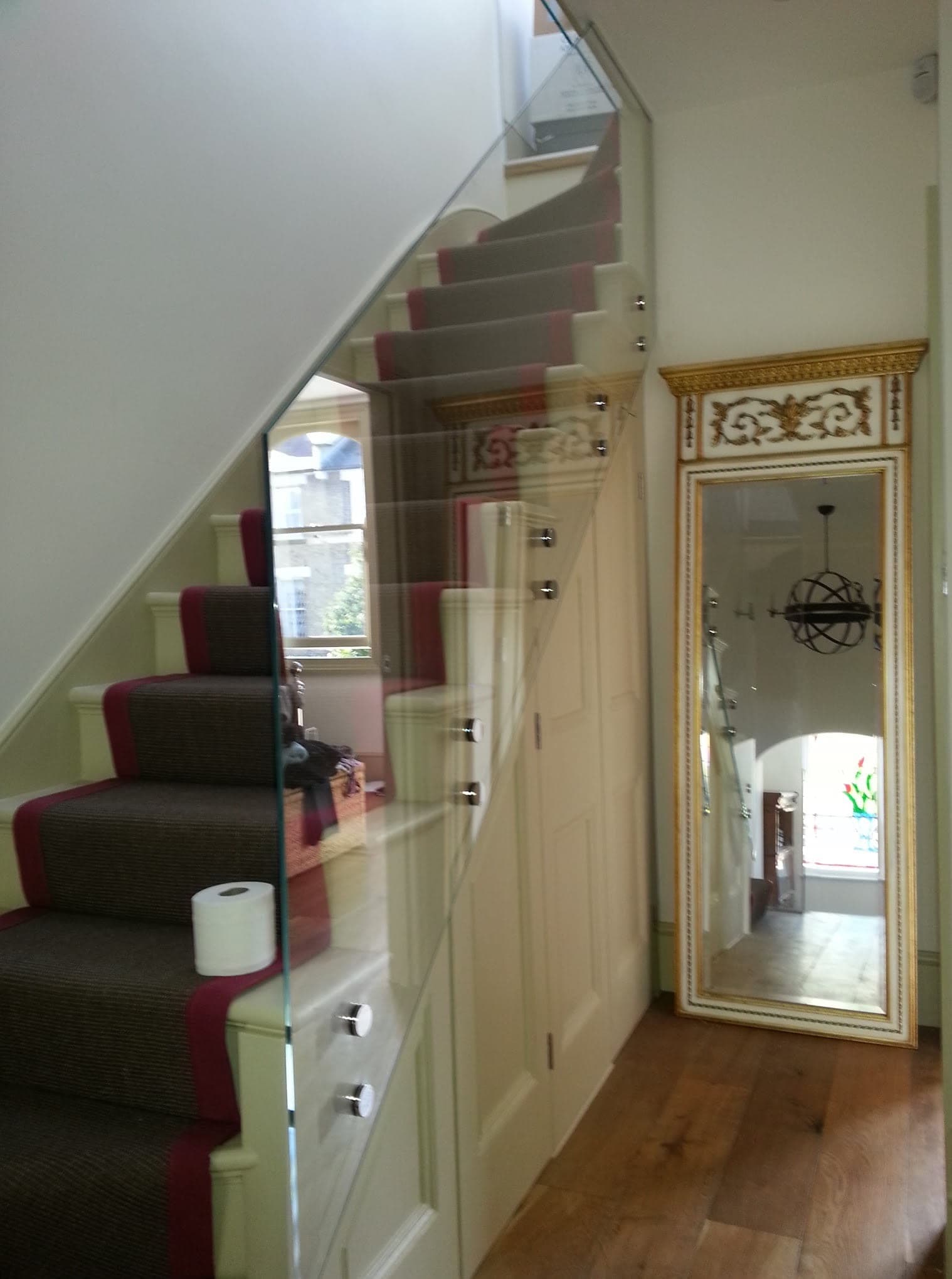 Glass balustrade running alongside a carpeted staircase with a stair runner