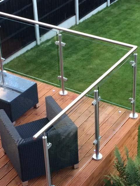 Garden decking balustrade with metal posts, a round handrail and glass infill panels