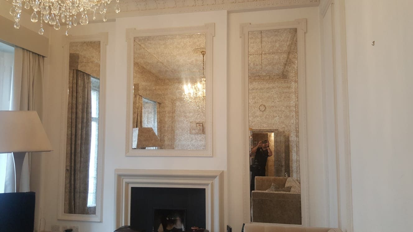 Two tall alcove mirrors flanking a fireplace in a panelled room