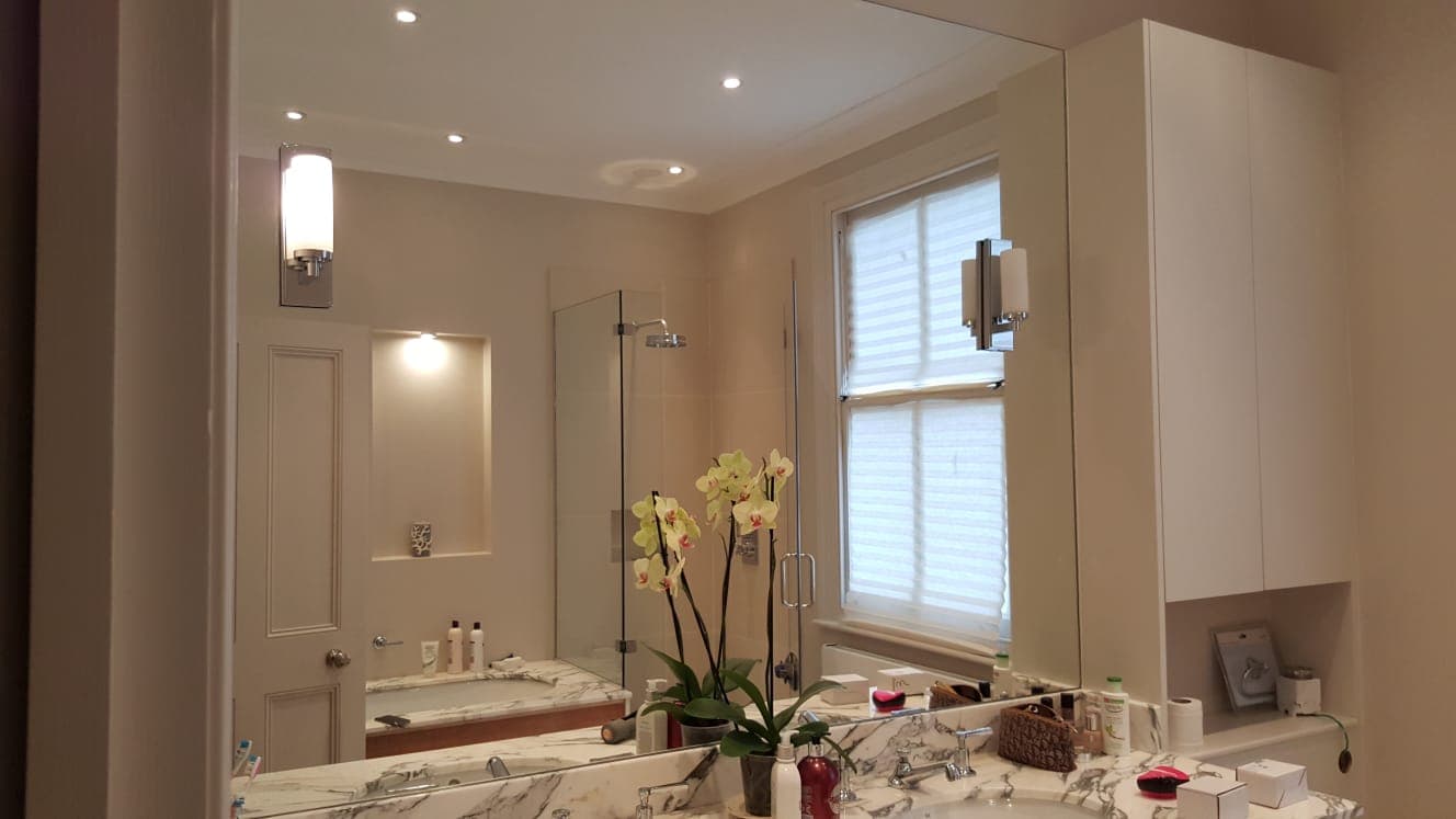 Bathroom mirror beside a recessed shelf and a shuttered window