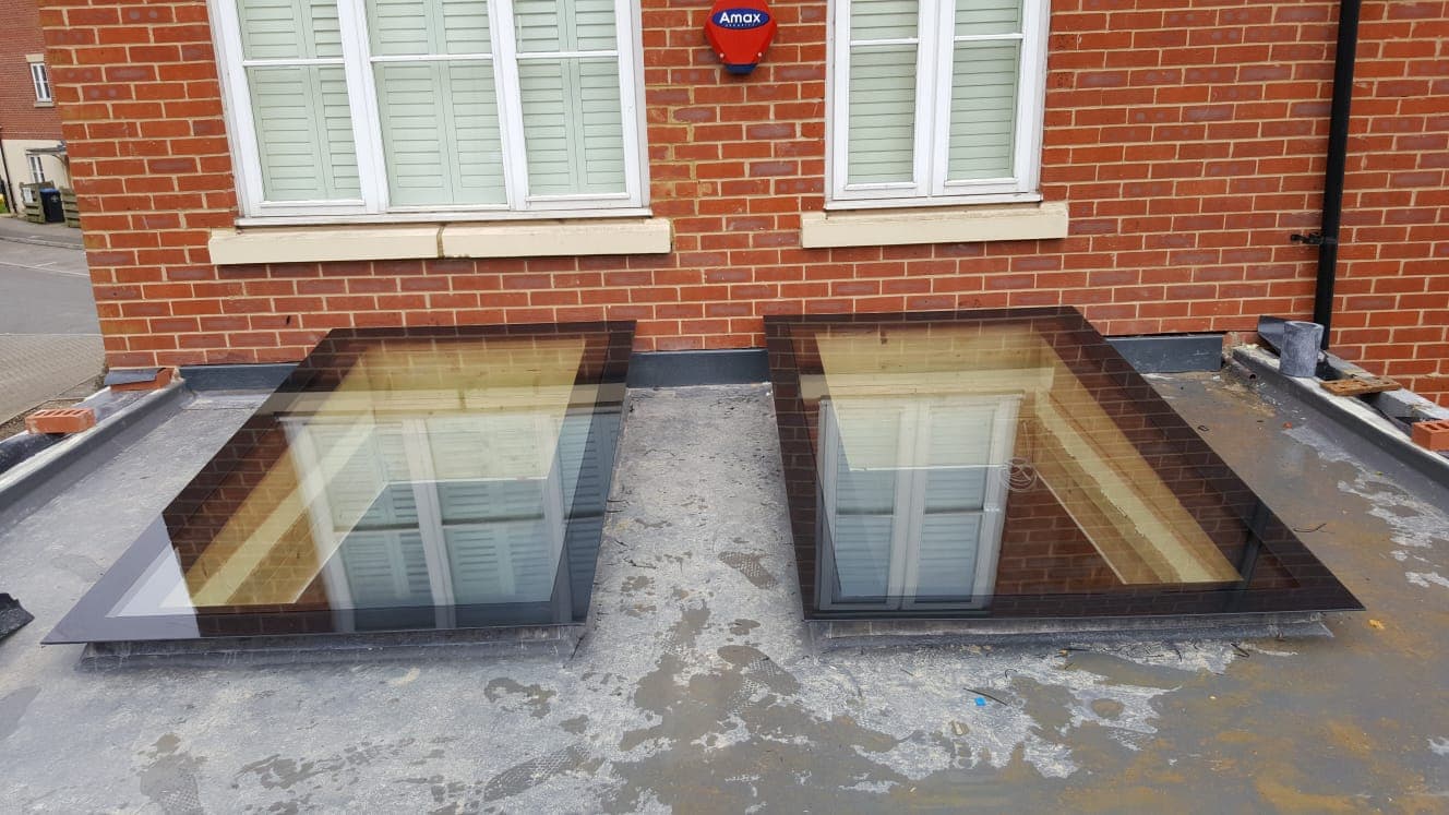 Two rectangular rooflights set into a flat roof against a red brick house
