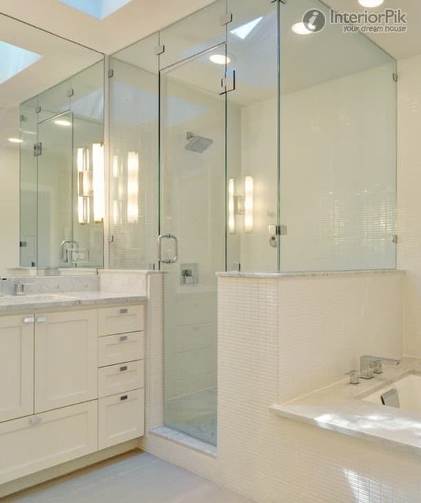 Frameless corner shower enclosure with a hinged door and chrome fittings, beside a white vanity unit with a stone top
