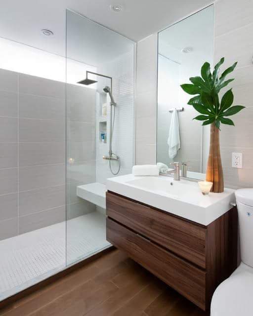Walk-in shower screen alongside a timber vanity unit, with a ceiling rainfall head and mosaic flooring