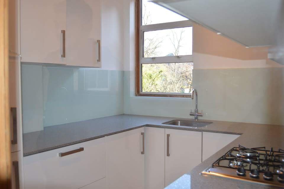 Pale blue glass splashback turning the corner of a kitchen and returning to the window