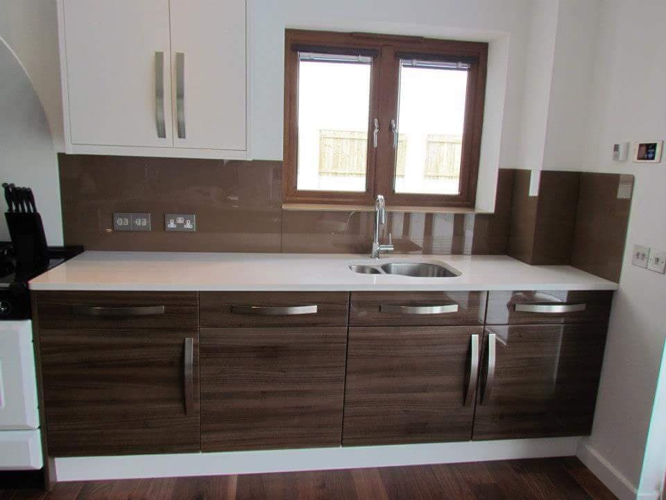 Brown coloured glass splashback with socket cut-outs, beside a kitchen window