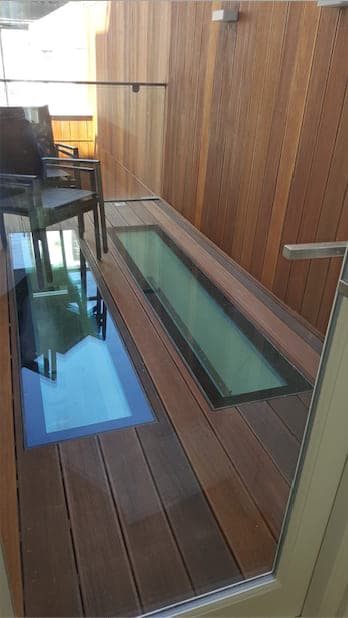 Two narrow walk-on glass strips set flush into a timber deck, letting daylight into the room below