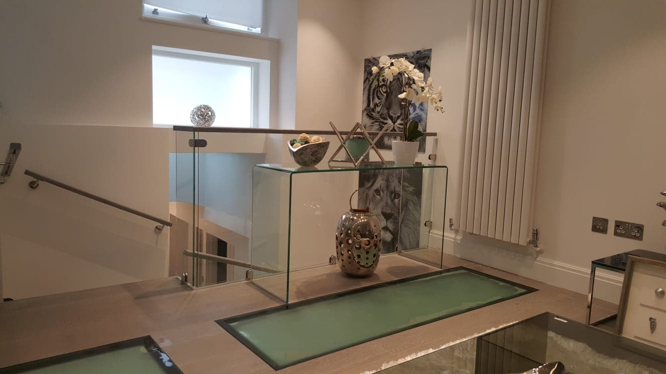 Interior landing with a sandblasted walk-on glass floor panel and a glass console table